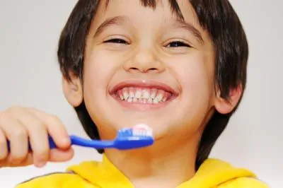 young boy smiling while brushing his teeth